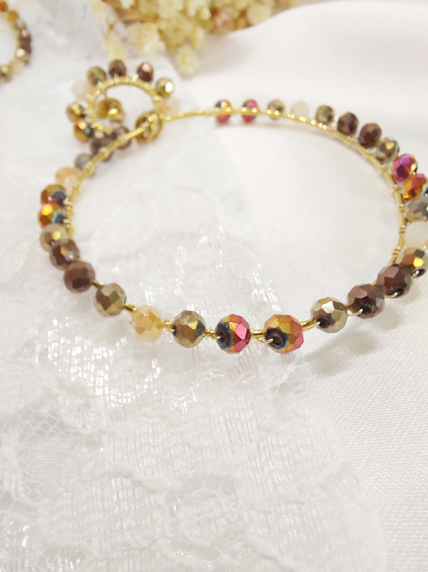 Boucles d'oreilles créoles en acier inoxydable et perles de verre dans les teintes de beige et marron. constitué de 2 anneaux, un petit et l'autre suspendus plus grand
