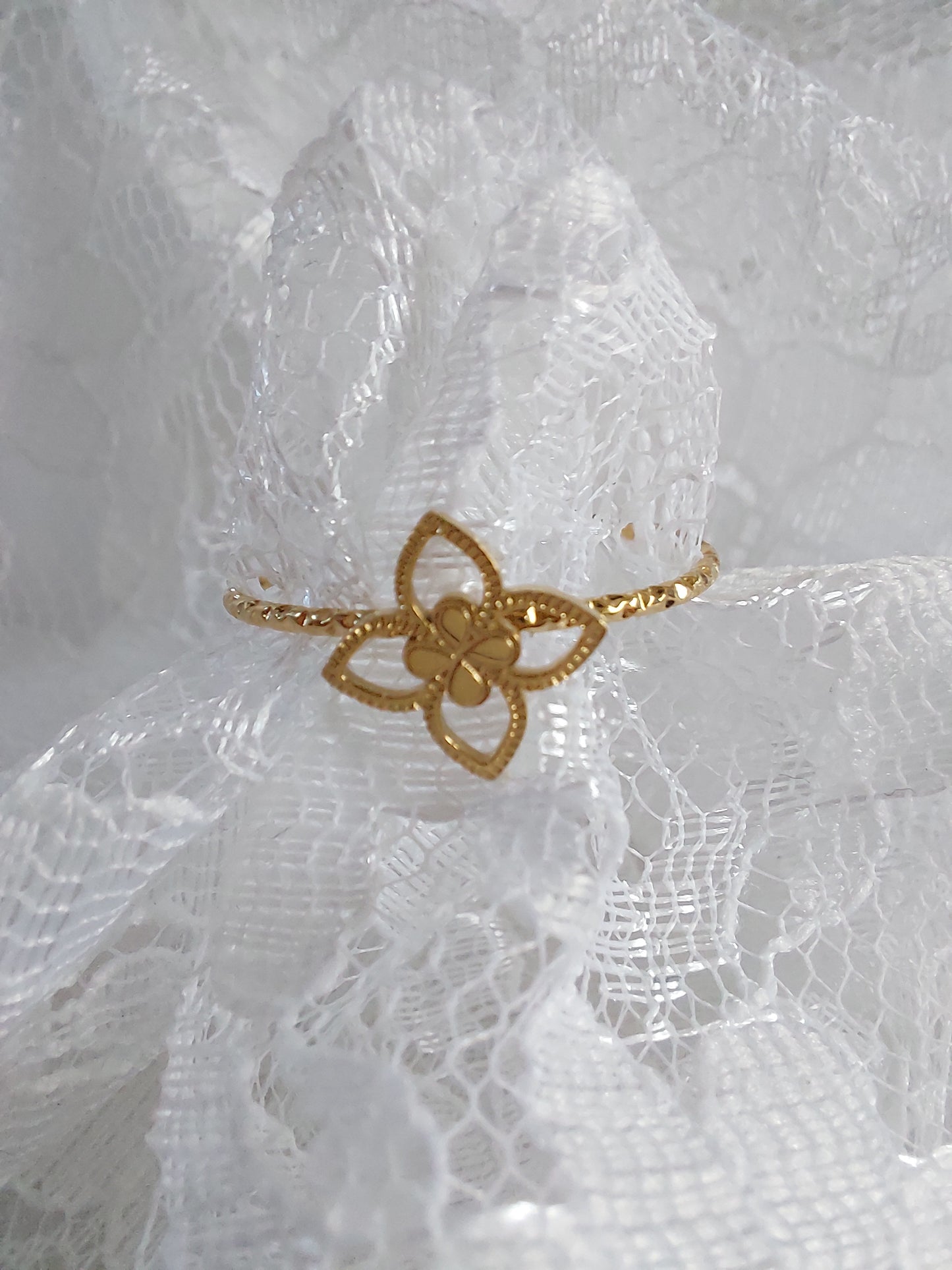 Bague en acier inoxydable doré avec un trèfle sur le dessus.