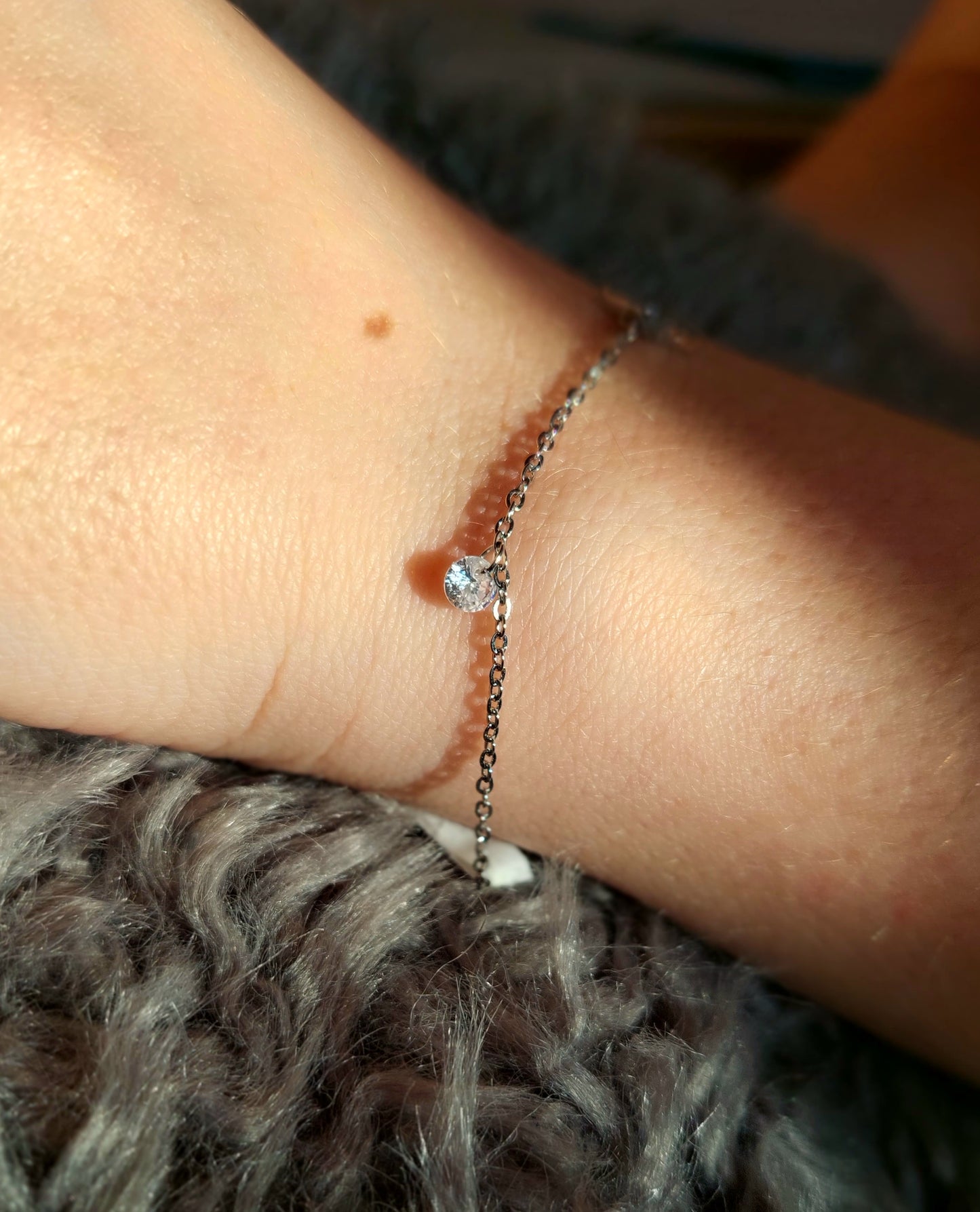 bracelet argenté avec une étoile et au centre un oxyde de zirconium et à côté une perle de Crystal 