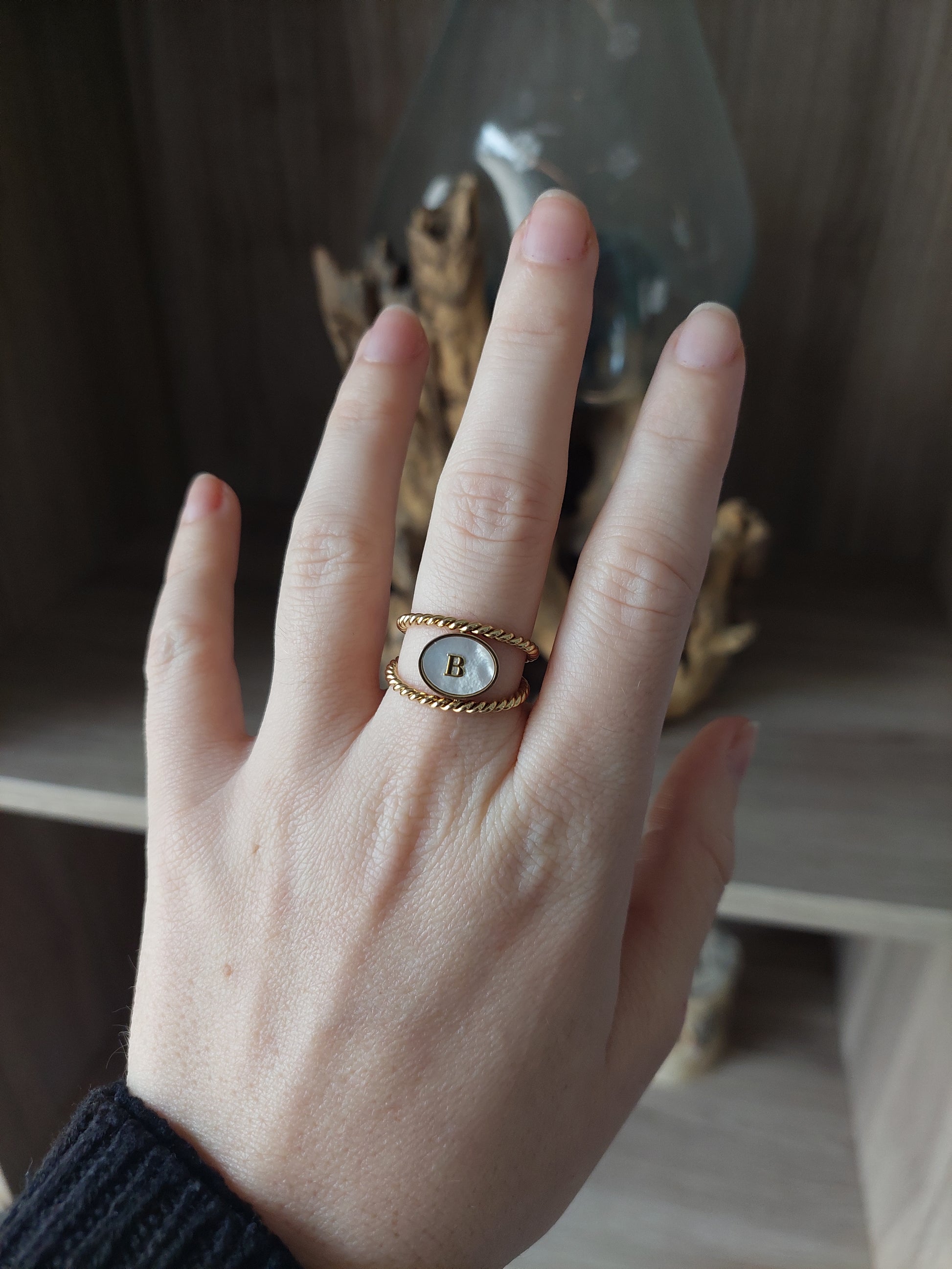 bijou personnalisable; bague en acier inoxydable doré avec un effet torsadé et un ovale nacré et une initiale  au centre