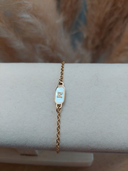 bracelet doré et un intercalé blanc nacré personnalisé avec une initial