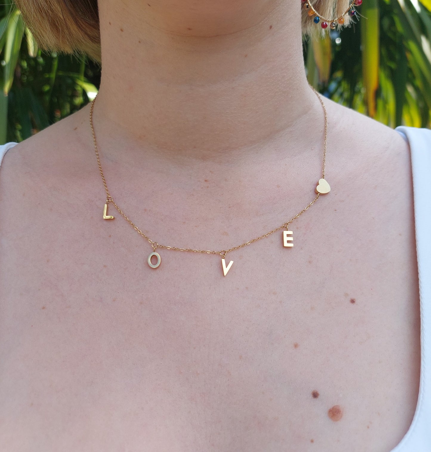 collier souvenir avec des lettres breloque formant le mot LOVE ainsi qu'un petit coeur en acier inoxydable