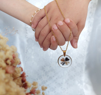 deux mains tenant un collier souvenir en forme de trèfles à quatre feuilles