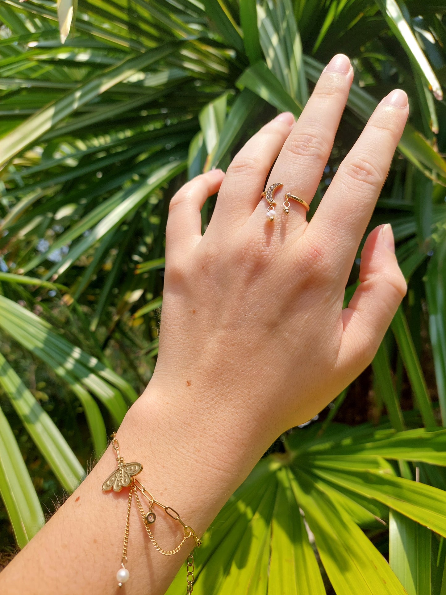 Bague réglable en acier inoxydable il y a une lune avec des strass et une perle blanche ainsi qu'une bille en acier inoxydable