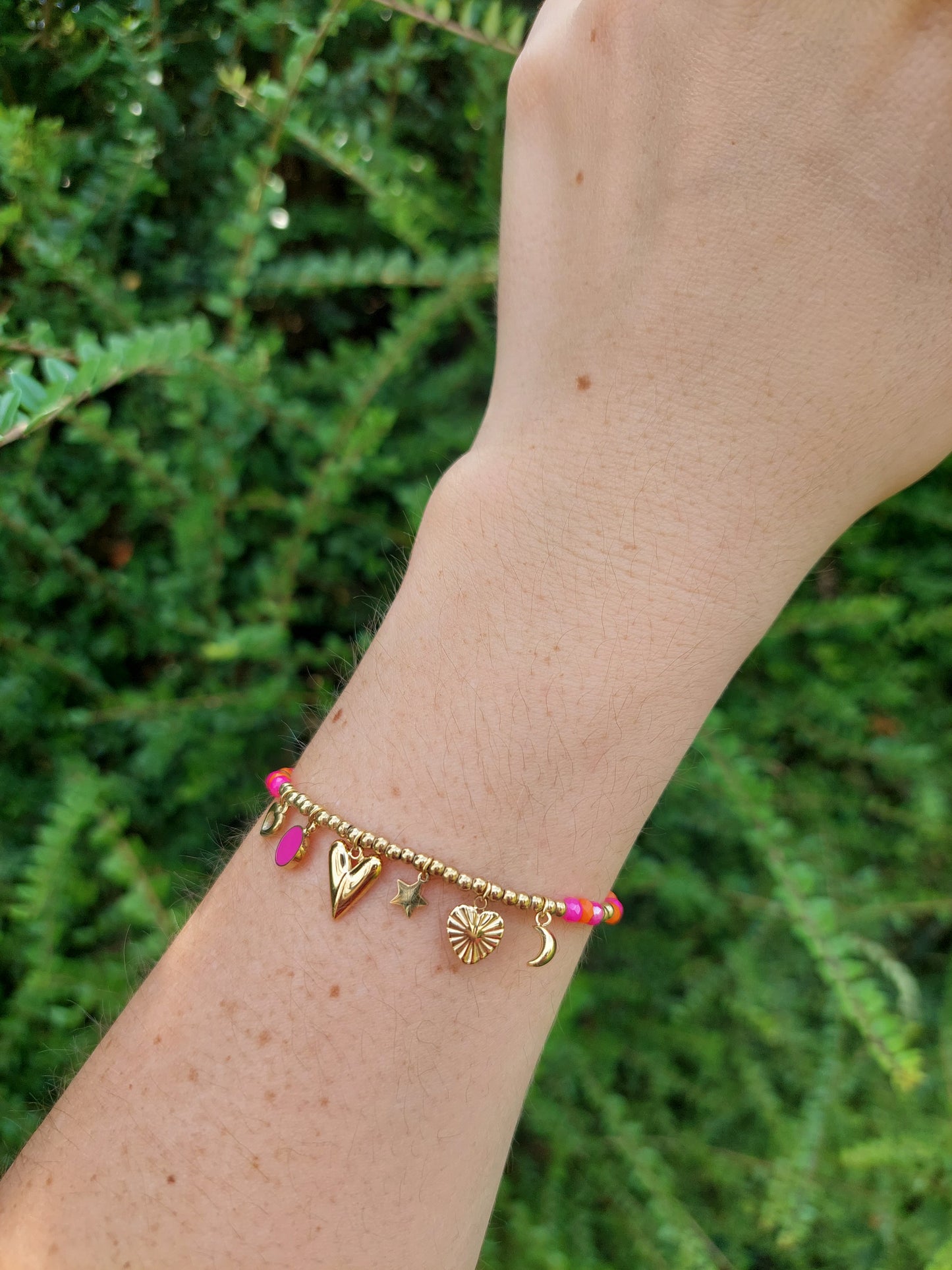 bracelet brelaoque avec des perle rose, orange et doré et des multiple breloque ( coeur, étoile, lune)