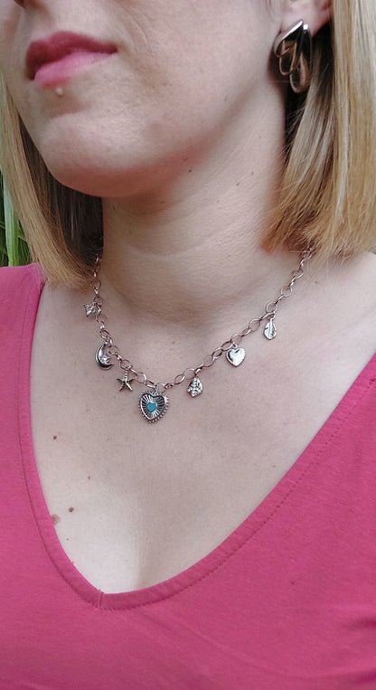 Collier en acier inoxydable argenté avec une chaine grosse mailles et plusieurs breloque (coeur, étoile de mer, lune, abeille)