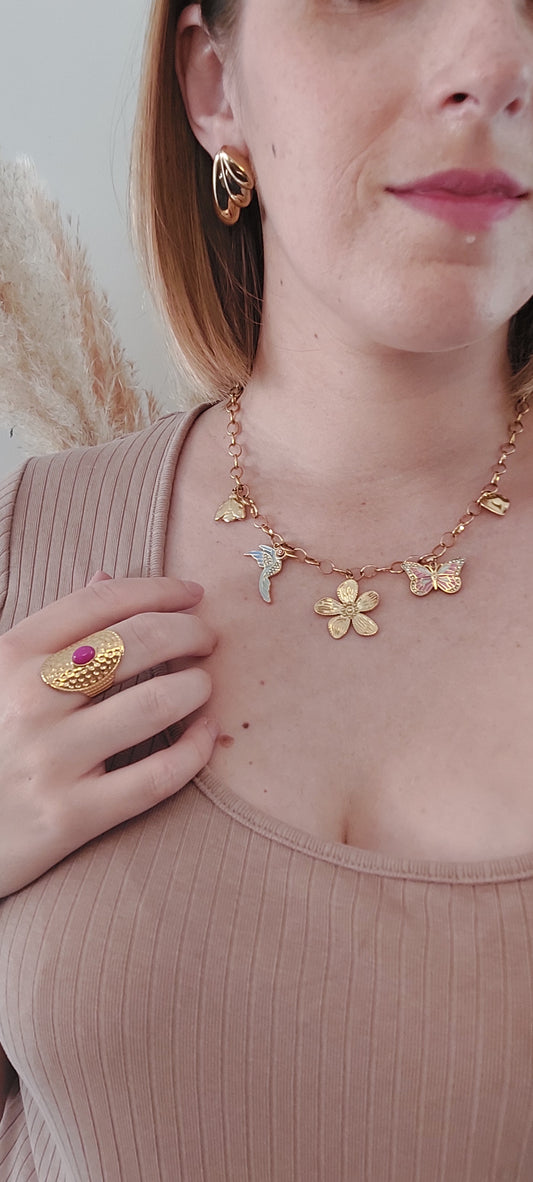 collier en acier inoxydable doré en grosse mailles et plusieurs charme. une fleurs central doré puis un oiseau blau, un papillon rose et une coccinelle et un coeur doré