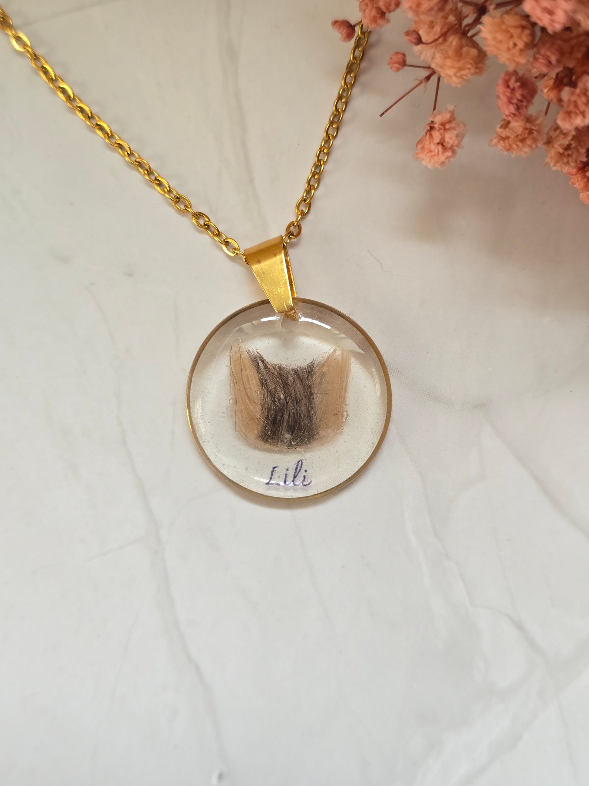 collier avec un pendentif rond et insertion de poils en forme de tête de chat