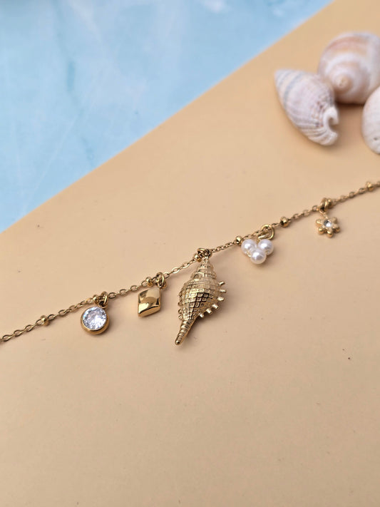 bracelet breloque avec coquillages, perle, strass et fleur.