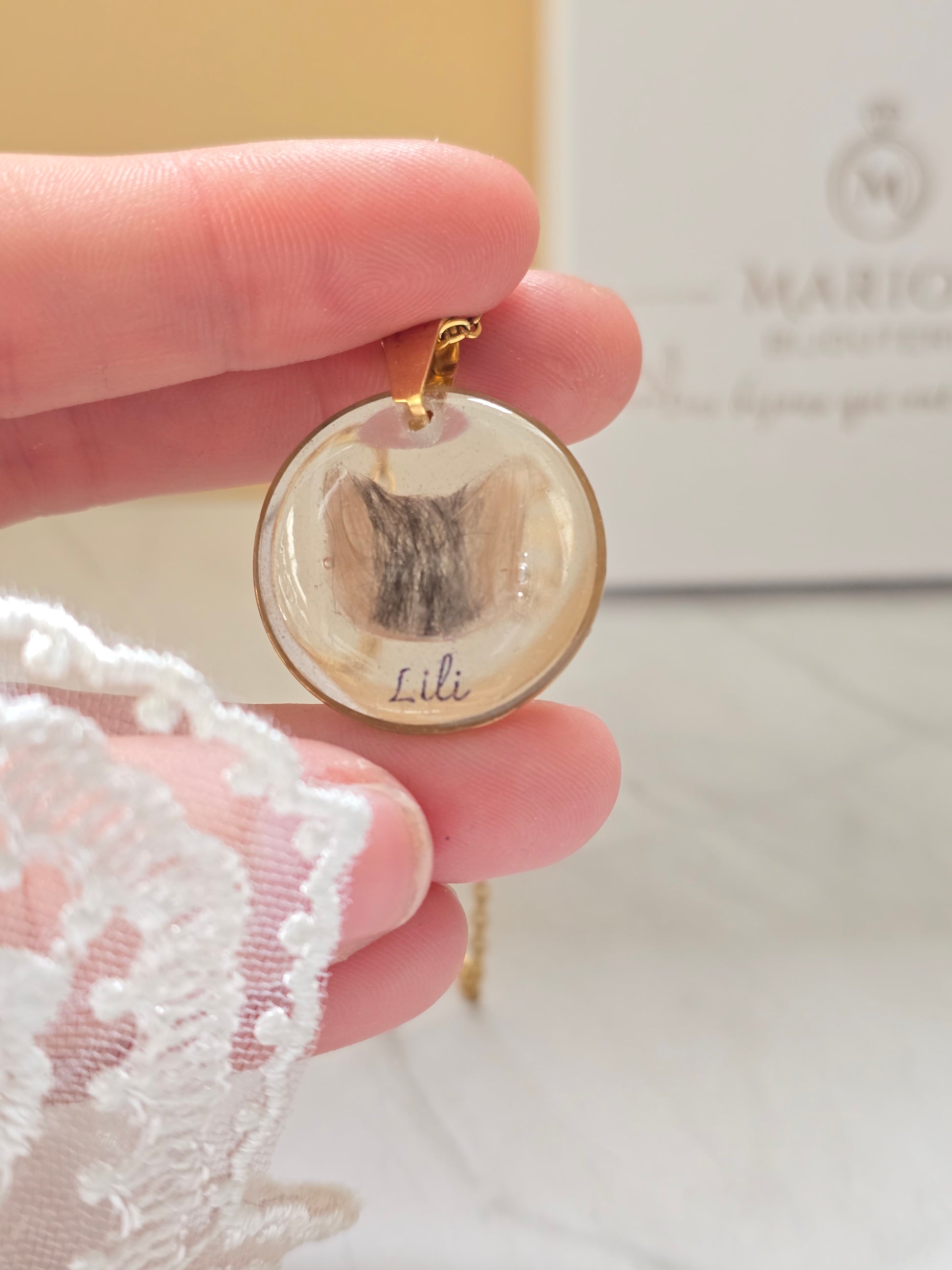 collier avec un pendentif rond et insertion de poils en forme de tête de chat