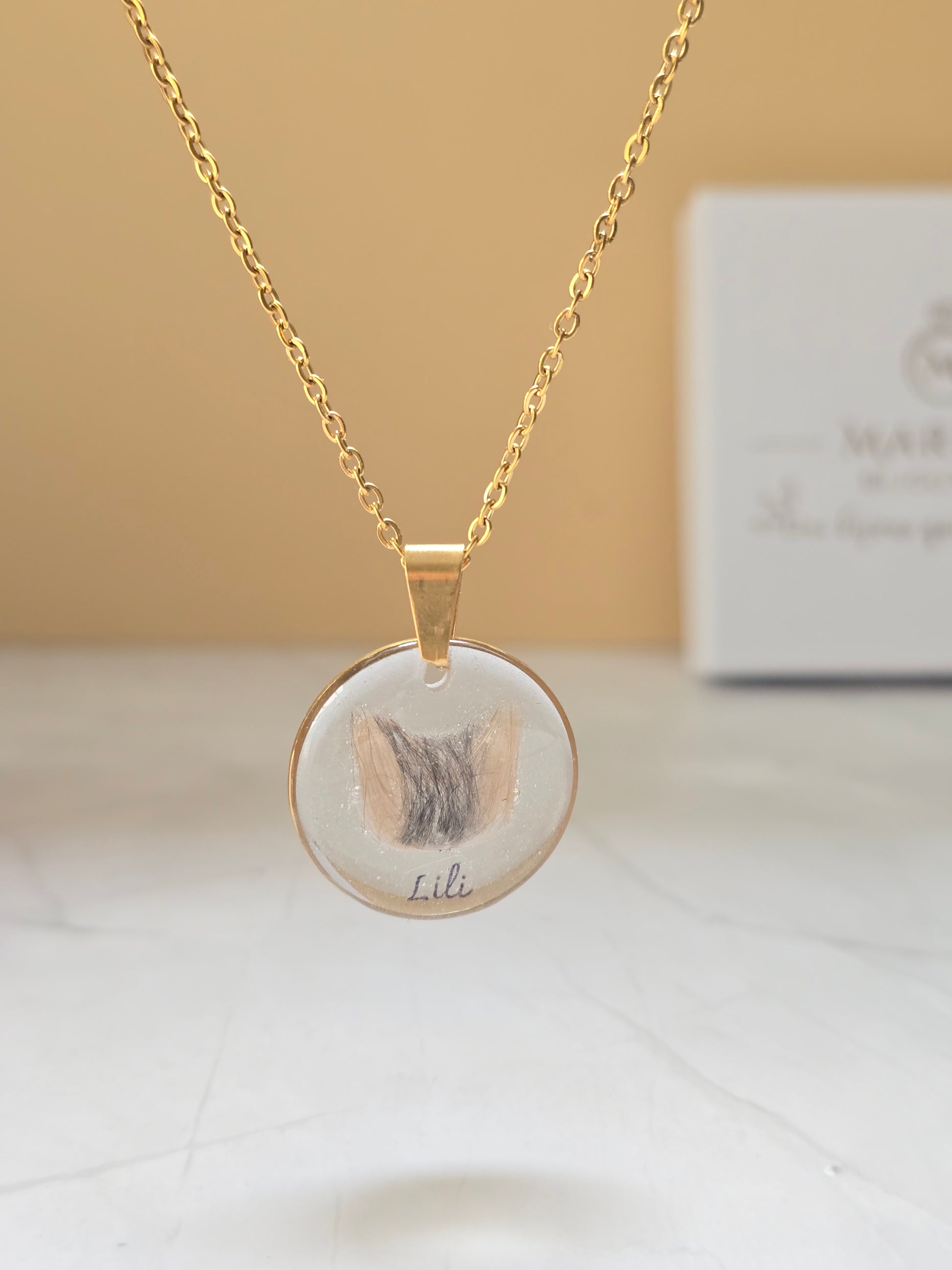 collier avec un pendentif rond et insertion de poils en forme de tête de chat