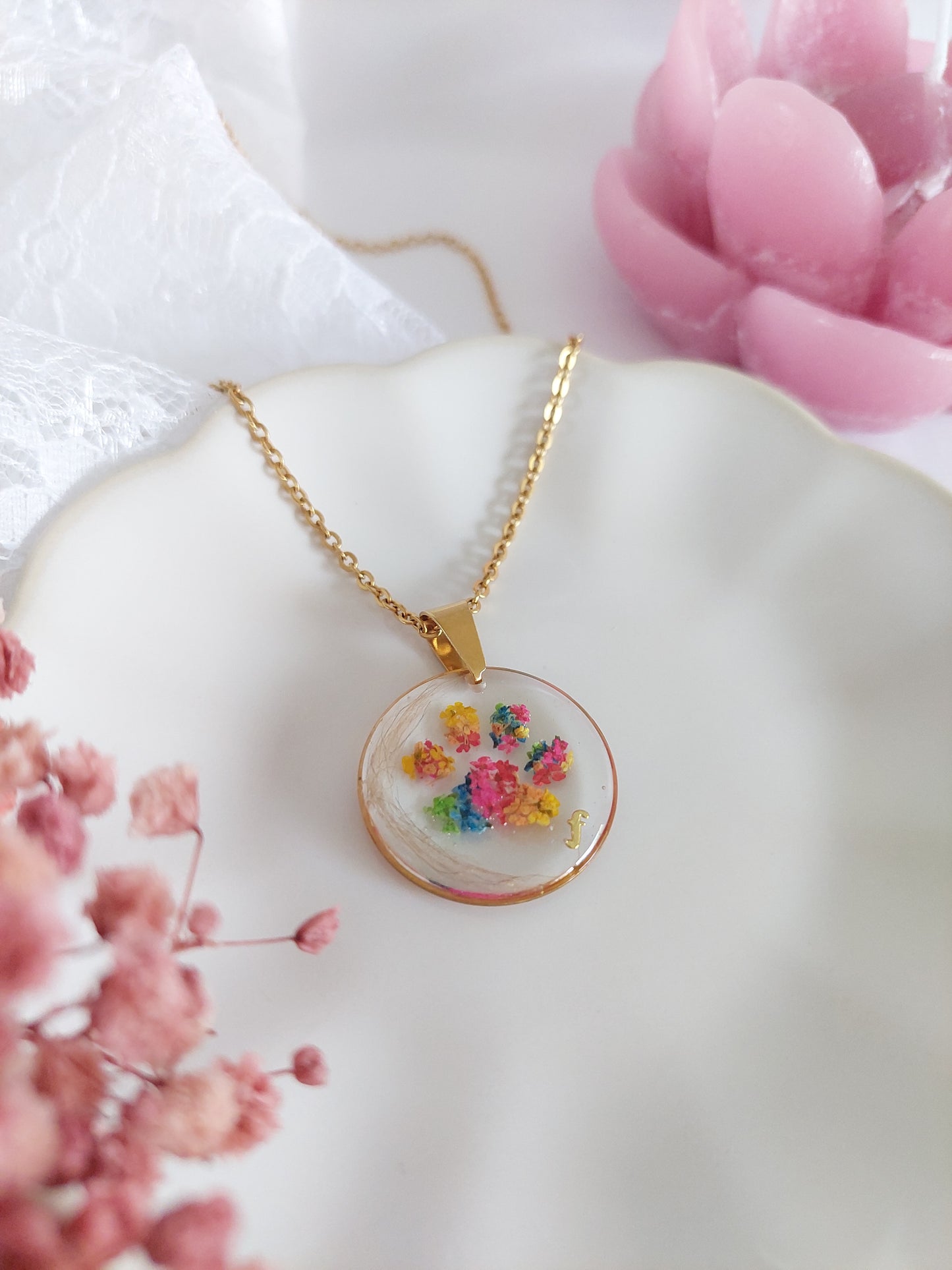 bijou souvenir collier doré avec une patte de chien ou chat en fleurs séchées avec un mèche de poils mis sur le coté du pendentif