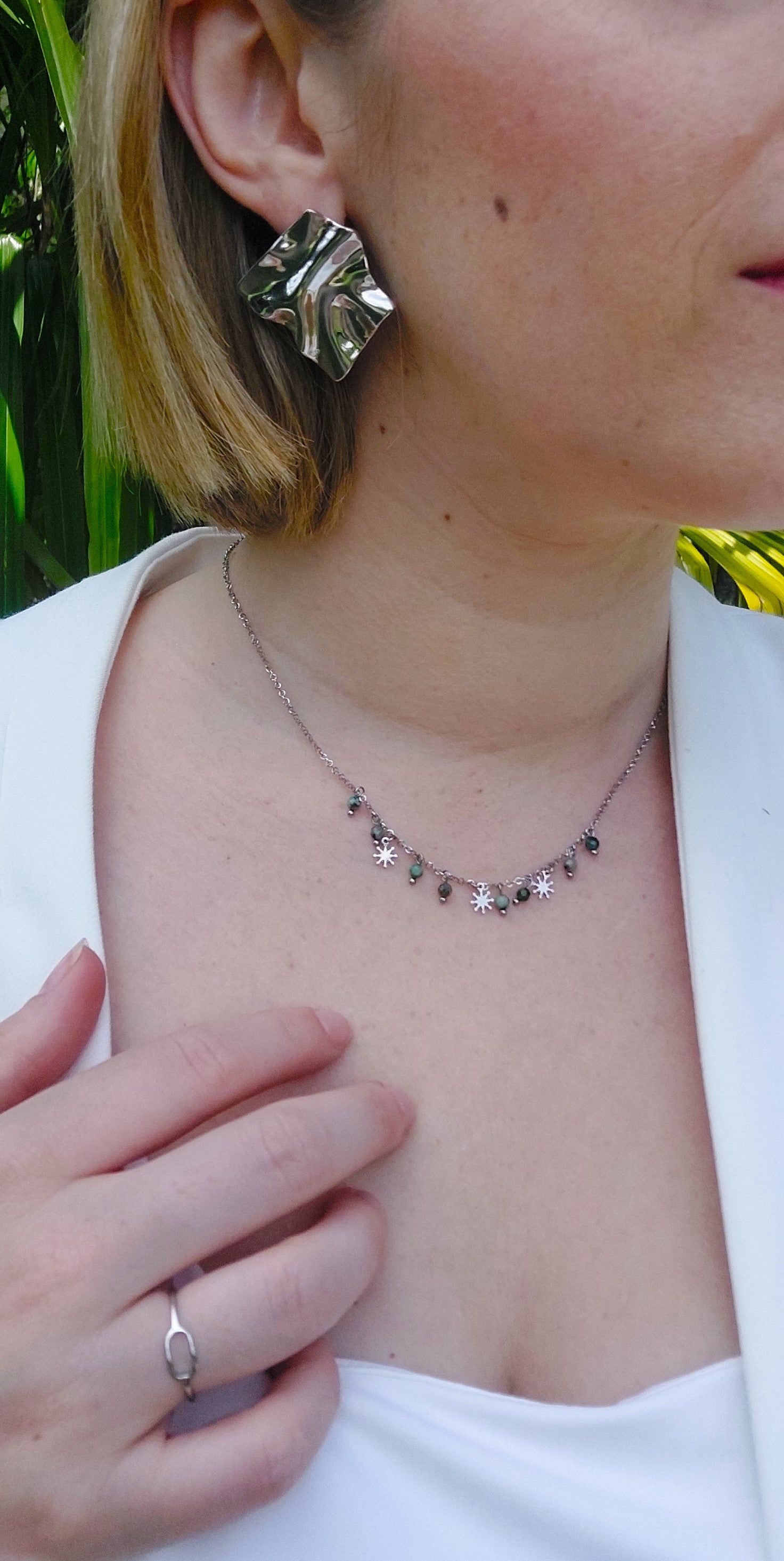 collier en acier inoxydable argenté avec des pampilles en forme de petits soleil et des perle en pierres naturels vertes.