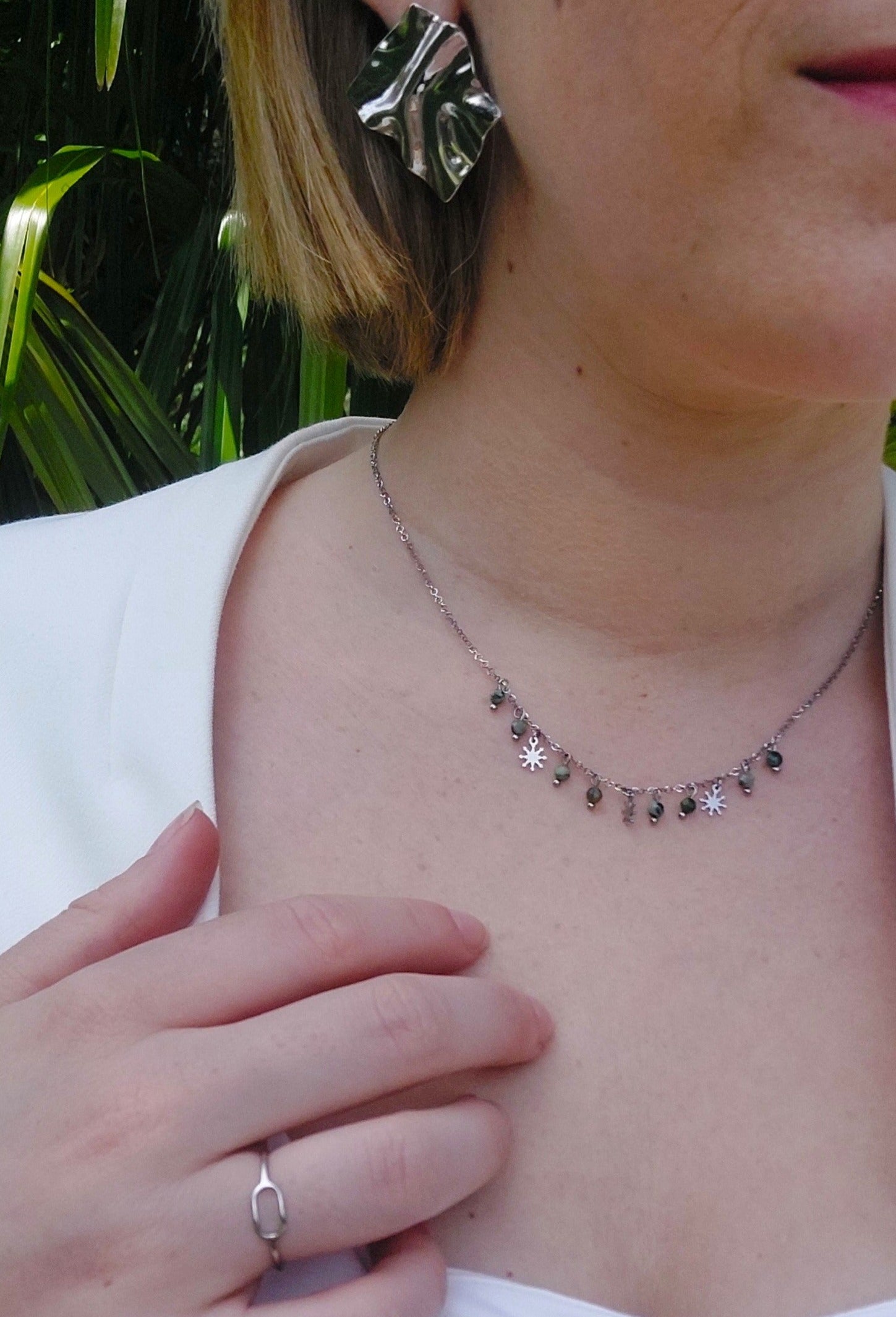 collier en acier inoxydable argenté avec des pampilles en forme de petits soleil et des perle en pierres naturels vertes.