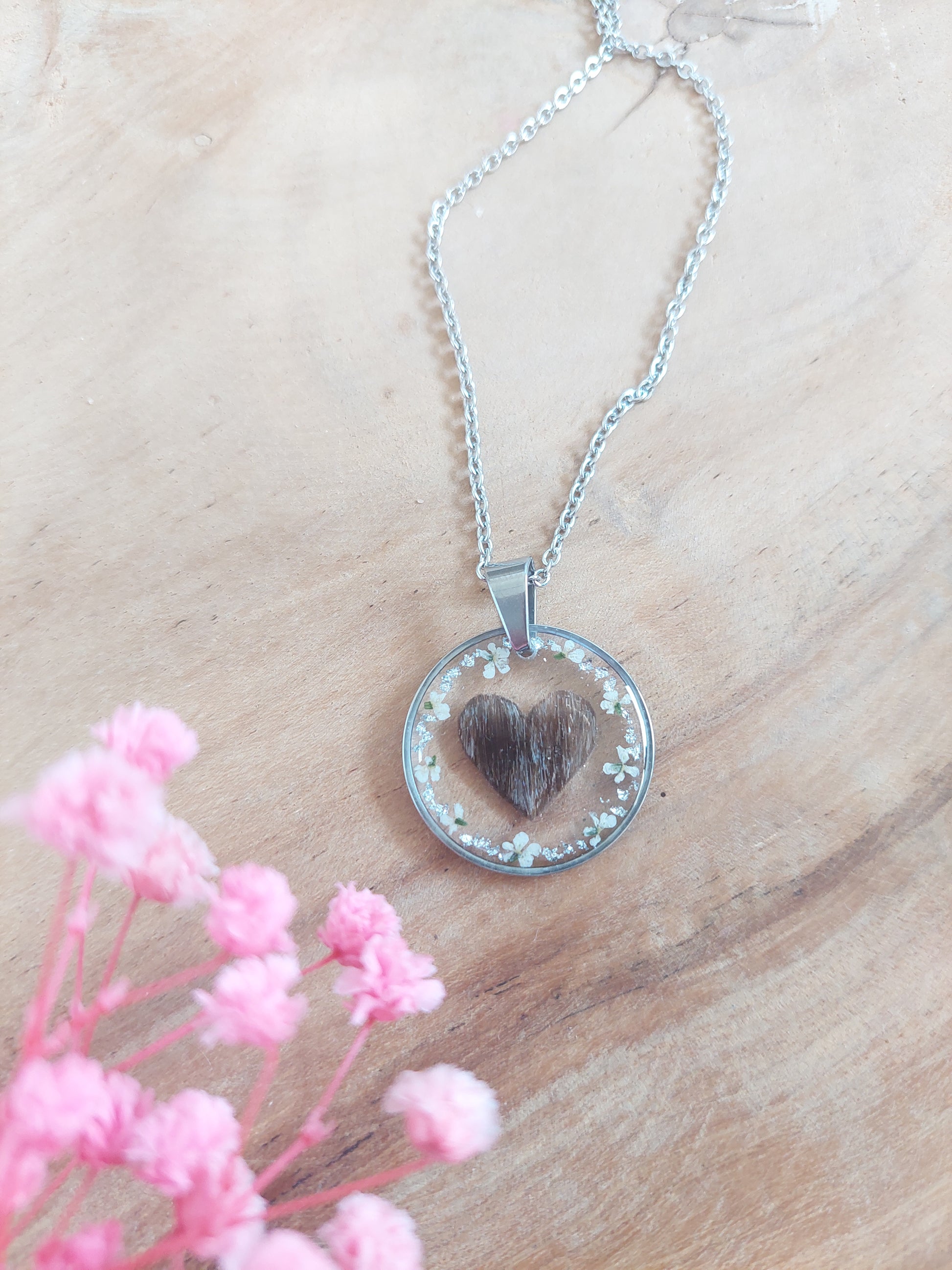 bijou souvenir: collier argenté avec un coeur réalisé en cheveux au centre et des fleurs blanche