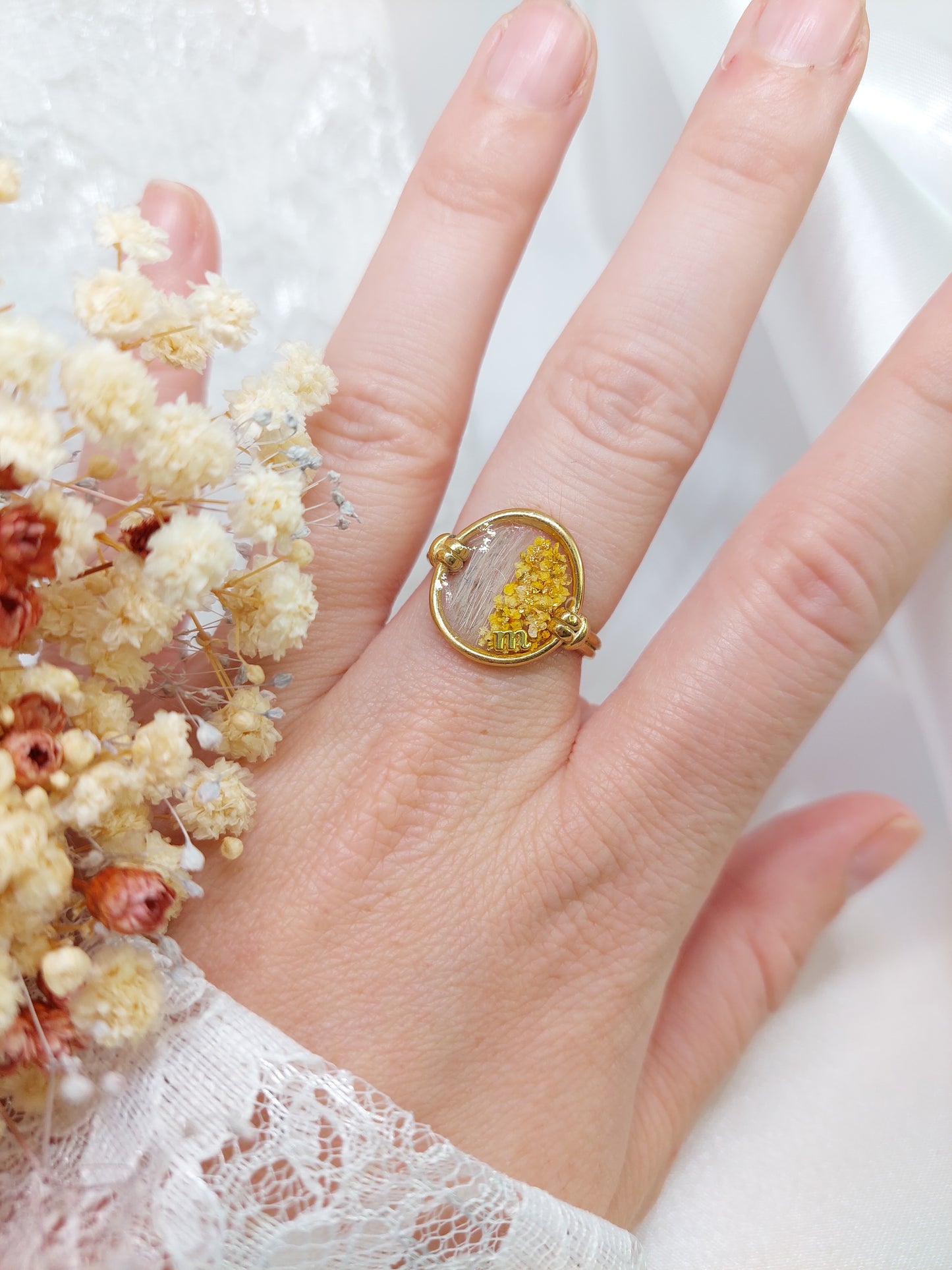 bague porté ovale doré avec insertion de poils et des fleurs jaunes