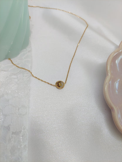 bijoux souvenir collier doré avec une mèche de cheveux dans le petit rond contenant également une initiale